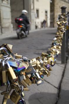 many padlocks are attached to the fence in front of a motorbike