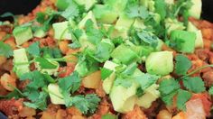 a black bowl filled with food and garnished with cilantro, avocado