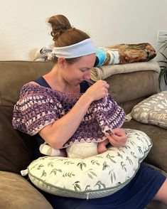 a woman sitting on a couch holding a baby