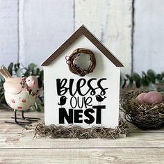 a birdhouse with a sign that says, bless our nest and two birds sitting in front of it