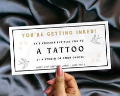 someone holding up a card that reads you're getting inked this voucherer entitled you to a tattoo at a studio of your choice