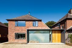 a brick house with an open front door and large glass windows on the side of it