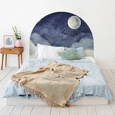 a bed with a blue blanket on top of it next to a night sky mural