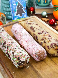 three doughnuts on a cutting board with christmas decorations in the background