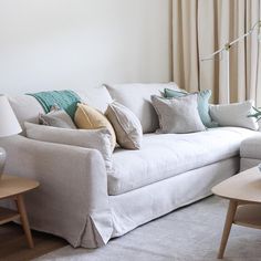 a living room with white couches and pillows on the back of it's sofa