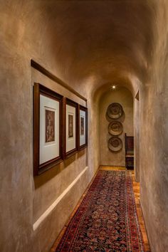 a hallway with two framed pictures on the wall and a rug in front of it