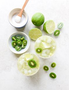 limes, kiwi slices and sugar in small bowls on a white counter top