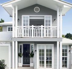 a gray house with white trim on the front door and windows, along with two balconies