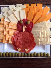 a turkey shaped platter with cheese, crackers and olives on a white plate