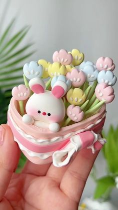 a hand holding a small toy in it's palm with flowers on the top