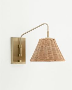 a light that is on the wall next to a basket shade lamp and white background