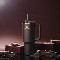 a black coffee mug sitting on top of a table next to chocolates and pieces of cake