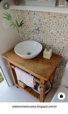 a white sink sitting next to a toilet in a bathroom under a mirror and wooden shelf