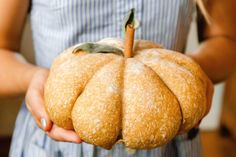 a person holding a doughnut shaped like a pumpkin