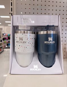 two travel mugs are sitting in a box on the shelf at a grocery store