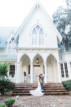 a bride and groom standing in front of a white church