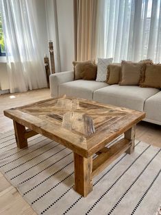 a living room with a couch, coffee table and rug in front of the window