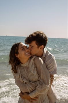 a man and woman kissing on the beach