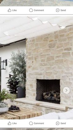 an outdoor living room with stone fireplace and white furniture