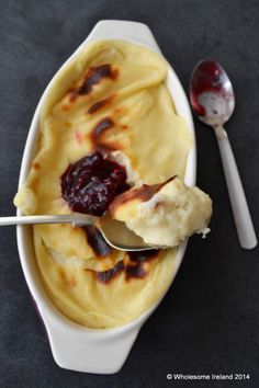 a spoon with some food in it next to a bowl filled with ice cream and jelly