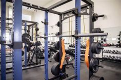 a gym with rows of weight machines and barbells in the center, all black and orange