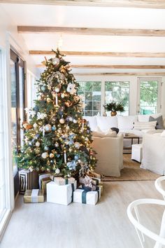 a living room with a christmas tree in the center and presents on the floor next to it