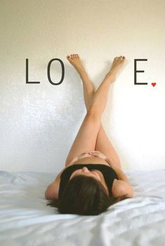 a woman laying on top of a bed with the word love written above her head