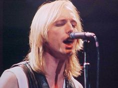 a man with blonde hair singing into a microphone