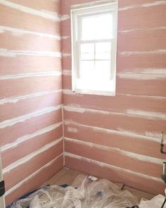 a room that has been painted pink with white stripes on the walls and floor, along with a window