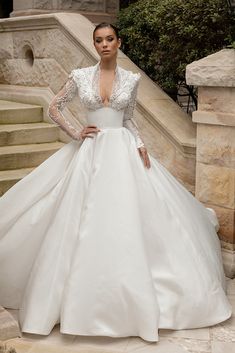 a woman in a white wedding dress standing on stairs with her hands on her hips