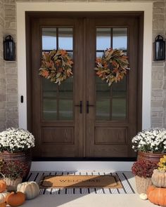 front door decorated for fall with pumpkins and flowers