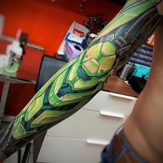 a man's arm with a green and blue tattoo design on his left arm