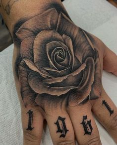 a person's hand with a rose tattoo on it and the letter m in black ink