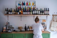 a woman standing in front of a counter filled with bottles