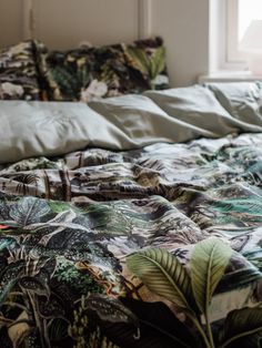 an unmade bed with green leaves on it