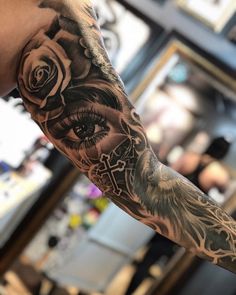 a man's arm with an eye and rose tattoo on it, in front of a mirror