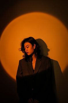 a woman standing in front of a wall with her shadow on the wall behind her