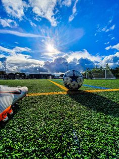 a soccer ball sitting on top of a field next to a goalie's leg