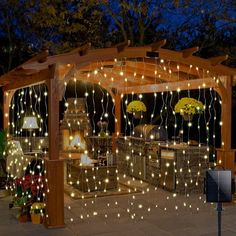 an outdoor kitchen is lit up with fairy lights