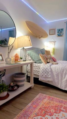 a room with a bed, mirror and rug on the floor next to a lamp