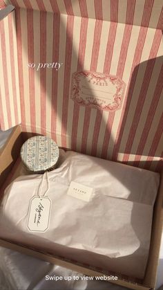 an open box with a tag on it sitting next to a striped bag and some other items