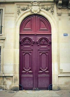 an old building with two red doors on the front