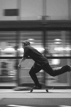 a man riding a skateboard down a street next to a tall building with lots of windows