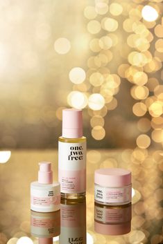 three bottles of skin care sitting next to each other on a table with lights in the background