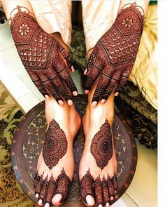 the feet and hands of a woman with henna tattoos