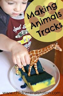 a young boy is playing with a toy giraffe on a plate that says making animals tracks