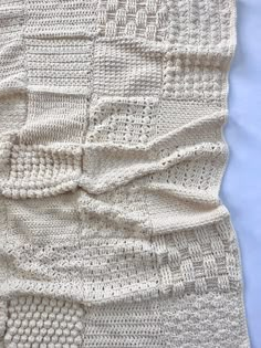 a white crocheted blanket laying on top of a bed