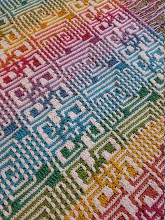 a multicolored crocheted blanket is laying on the floor