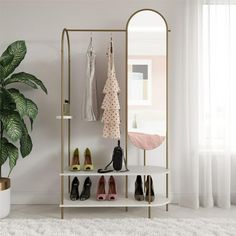 a white shelf with shoes on it next to a potted plant and a mirror