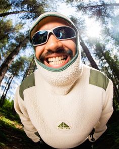 a man wearing sunglasses and a white jacket in the woods